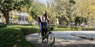 asiático mujer de negocios en bicicleta Vamos a trabajo a oficina. bicicleta viajando, contento mujer de negocios utilizando eco transporte, concepto de eco estilo de vida foto