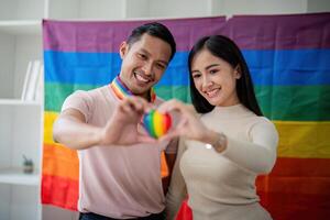 Young gay male and girl friend hands holding rainbow heart with smile face. LGBT, human rights and equality social photo