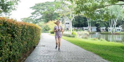 Woman active Asian woman in sportswear listening to music while running or jogging in the park in the morning photo