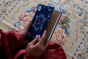 cerca arriba ver de un musulmán mujer participación el Corán o sura yaseen o yasin libro foto