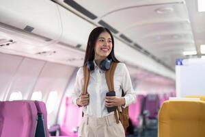 Alone Asian woman passenger traveling by plane. happy traveler on board. Solo travel concept photo