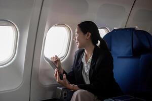 Successful young asian business woman sits in airplane cabin plane and working from anywhere. Flying at first class photo