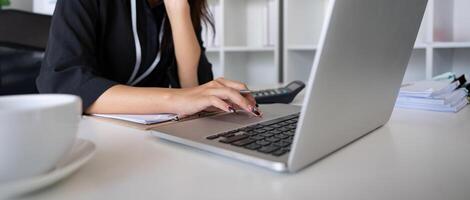 mujer de negocios trabajando utilizando ordenador portátil computadora a grabar y impresión información para un márketing plan analizar el equilibrar sábana reporte financiero declaración foto