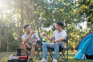 masculino gay Pareja asiático de viaje con tienda cámping al aire libre y varios aventuras estilo de vida excursionismo activo verano vacaciones. Bebiendo café y hablando juntos foto