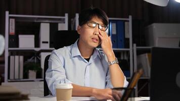 Exhausted Asian young businessman worker working on table in office. video