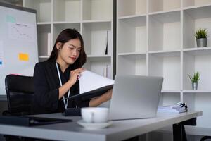 Beautiful asian businesswoman woman using calculator and laptop for doing finance on an office desk, tax, report, accounting, statistics, and analysis research concept photo