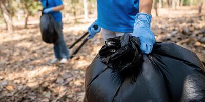 Young people friend volunteer collecting garbage plastic bottles to trash bags. environmental care ecology concept photo