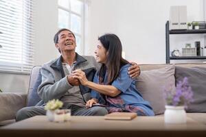 Happy mature husband and wife sit rest on comfortable sofa in living room enjoy talking, smiling elderly couple relax on couch at home chat speak laugh on leisure weekend photo