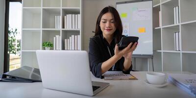 Businesswoman accountant using calculator and laptop for financial data saving in office room, Business financial, tax, accounting concept photo