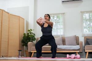 Overweight woman enjoying a fitness workout at home. Fat, plump woman and squatting on an exercise mat in the living room photo