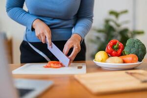 Fat woman cook in kitchen and chopping fresh vegetable on chopping board. health care concept Eat healthy food to lose weight photo