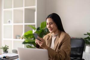 Work from home. Businesswoman using laptop computer and smartphone in her room. Eco friendly businesswoman working on desk, freelance, green room area, sustainable lifestyle concept photo