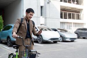 asiático empresario en un traje es montando un bicicleta en el ciudad calles para su Mañana conmutar a trabajar. eco transporte concepto, sostenible estilo de vida concepto foto