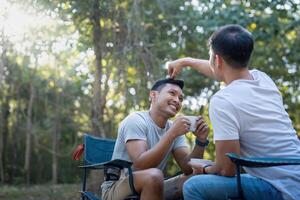 masculino gay Pareja asiático de viaje con tienda cámping al aire libre y varios aventuras estilo de vida excursionismo activo verano vacaciones. Bebiendo café y hablando juntos foto