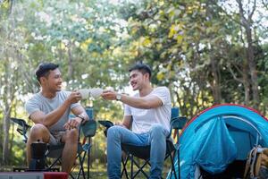 masculino gay Pareja asiático de viaje con tienda cámping al aire libre y varios aventuras estilo de vida excursionismo activo verano vacaciones. Bebiendo café y hablando juntos foto