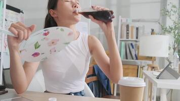 een Aziatisch vrouw opstarten arbeider is werken in heet temperaturen Bij bureau in klein bedrijf kantoor in zomer, ongemakkelijk met Nee lucht conditioner, blazen wind met fans, drinken water, en zweten. video