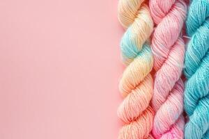 AI generated Multi colored yarn on a pastel pink background with copy space. Accessories for knitting and needlework photo