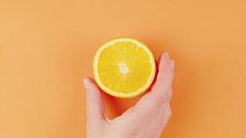 female hand put a cut lemon on the table fresh aroma citrus on orange background video