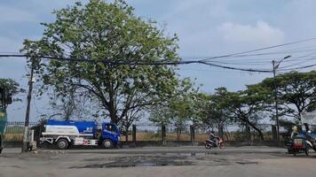 Marunda, Indonesia on July 8 2023. Roadside atmosphere on the northern outskirts of Jakarta. Where there are still paddy fields and fields, containers and heavy vehicles milling about video