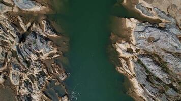 Aerial view of a serene river winding through weathered rocks in the Annamite Range, Vietnam, showcasing natural erosion patterns and tranquil waters in a high resolution video clip