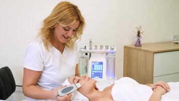 närbild av skön kvinnas ansikte under ultraljuds- skala hud procedur på spa salong. ultraljud ansiktsbehandling peeling. ultraljuds- ansiktsbehandling rensning på kosmetologi. . minsk, Vitryssland - november 10, 2022 video