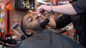 il parrucchiere tagli il del cliente barba con un' clipper. uomo nel il barbiere. il professione di barbiere. video