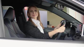 Porträt von ein jung zuversichtlich Frau Sitzung im ein Neu Auto beim ein Auto Händler video