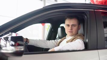 retrato do uma jovem confiante homem sentado dentro uma Novo carro às uma carro concessionária video