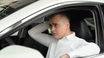 Portrait of a young confident man sitting in a new car at a car dealership video