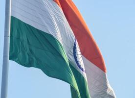 India flag flying high at Connaught Place with pride in blue sky, India flag fluttering, Indian Flag on Independence Day and Republic Day of India, tilt up shot, Waving Indian flag, Har Ghar Tiranga photo