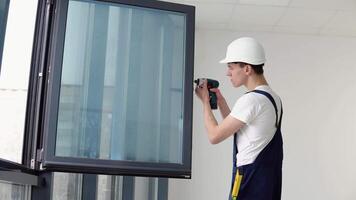 das Magier installiert das Schrauben im das Fenster Rahmen mit ein Schraubendreher video