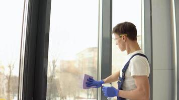 Young serviceman in protective uniform and glasses washes windows video