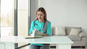 kvinna läkare bär medicinsk täcka och stetoskop skrivningar en medicinsk historia i en anteckningsbok video