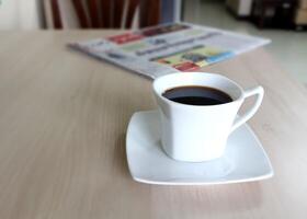 Coffee cup and newspaper on the wooden table. photo