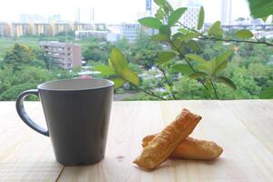 Coffee cup and pie on wooden table in the terrace. Looking out to the cityscapes. photo