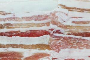 Meat from the sides and belly of a pig, having distinct strips of fat. Bacon, sliced pork texture background. photo