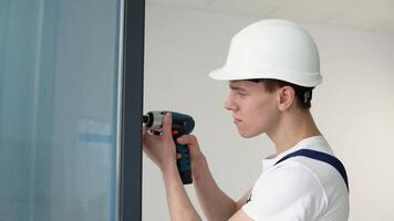 das Magier installiert das Schrauben im das Fenster Rahmen mit ein Schraubendreher video