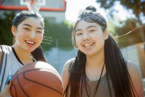 AI generated Two asian girls smiling outdoors holding a basketball joyfully, women in sports competitions, athletic excellence, competitive spirit photo