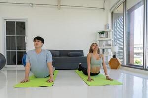 Young Asian Couple Doing Yoga at Home Together photo