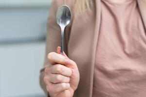 Metallic empty eating spoon in a human right hand with clipping path isolated on white photo
