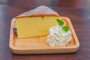 A Slice of cheese cake served with whipped cream on a wooden plate. photo
