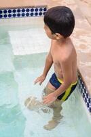 contento indio chico nadando en un piscina, niño vistiendo nadando disfraz a lo largo con aire tubo durante caliente verano vacaciones, niños chico en grande nadando piscina. foto