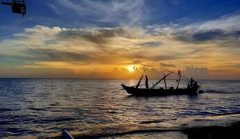 a fishing boat is in the water at sunset photo