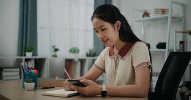 Side view, Female writer sitting at desk writing noting information to diary from smartphone at home, creative thoughts to journaling, idea and inspiration photo