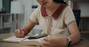 Selective focus, Hands of Female writer sitting at desk writing information on diary notebook while reading book at home, creative thoughts to journaling, idea and inspiration photo