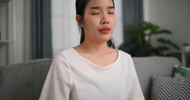 Selective focus, Young attractive woman sitting resting on sofa with eyes closed do meditation in the living room at home, deep relaxation practice, breathing fresh air photo