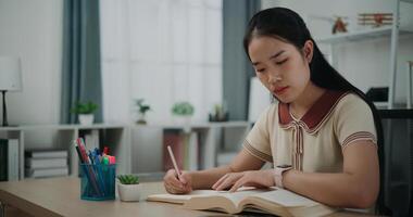 Selective focus, Female writer sitting at desk writing information on diary notebook while reading book at home, creative thoughts to journaling, idea and inspiration photo