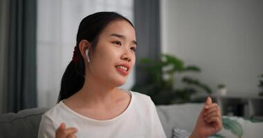 Selective focus, Relaxed young woman wear wireless headphones enjoying rest sitting on sofa in living room listening to music and dancing at home photo