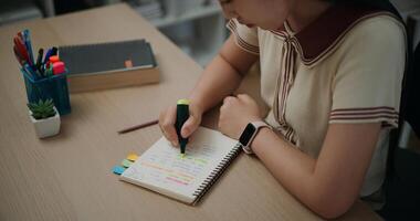 High angle view, Selective focus, Hands of Female writer sitting at desk writing and highlighting important things in diary with green marker in living room, creative thoughts to journaling photo