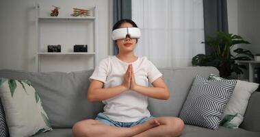 Selective focus, Relaxed young woman wear VR goggles meditating enjoying rest on sofa in living room at home, breathing fresh air, photo